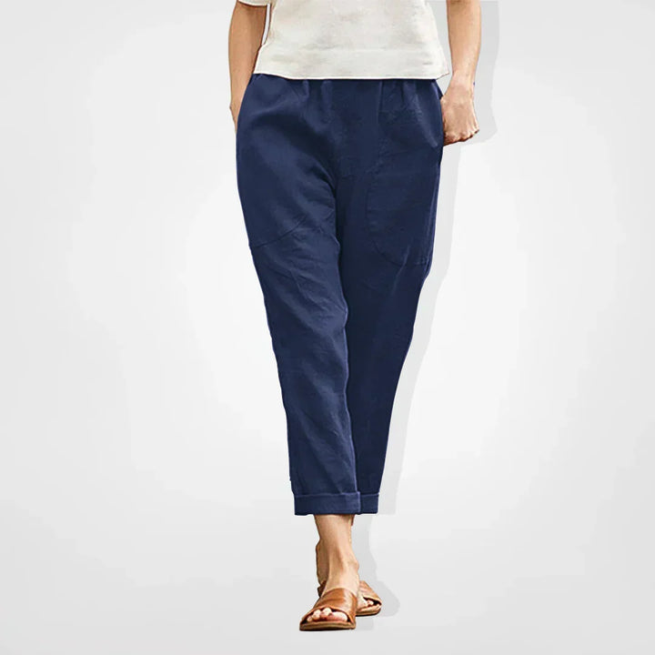 Woman wearing dark blue cropped tapered trousers with cuffed hem and white top