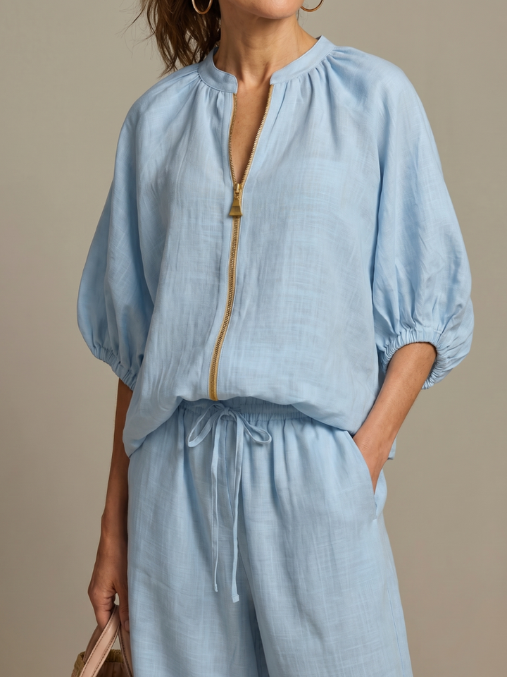 Close-up of woman wearing light blue zip-front blouson top and drawstring waist pants