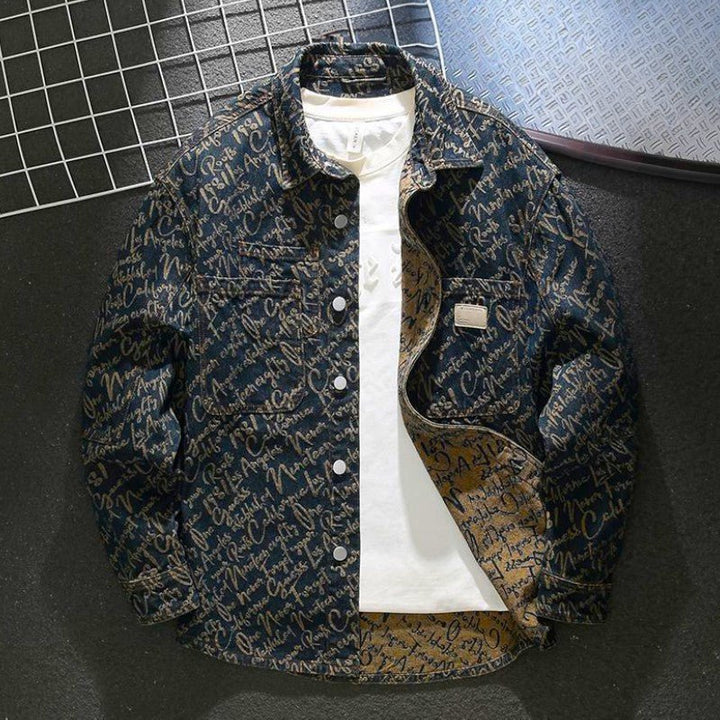 Men's embroidered script denim jacket laid flat on a dark surface
