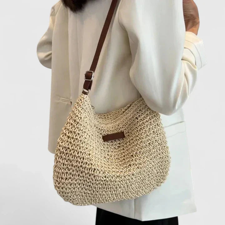 Side angle of women's woven straw crossbody bag showing structural depth and shoulder strap
