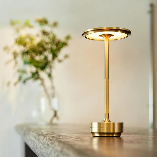 Gold brass cordless rechargeable table lamp glowing on a wooden surface