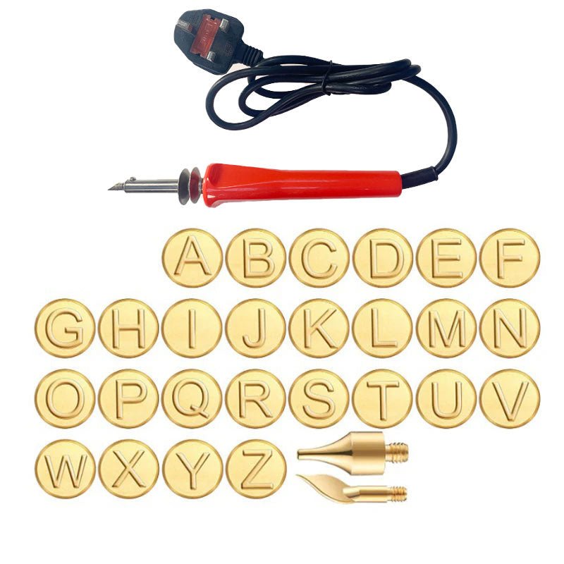DIY engraving set with brass alphabet heads laid out alongside a red soldering iron and power cable