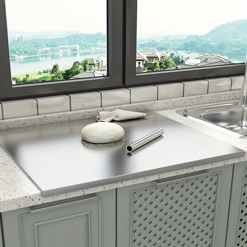 Stainless steel chopping board on modern kitchen countertop with dough