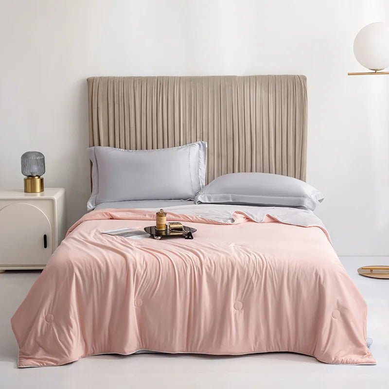 Soft pink reversible cooling blanket spread across a neutral bedroom bed