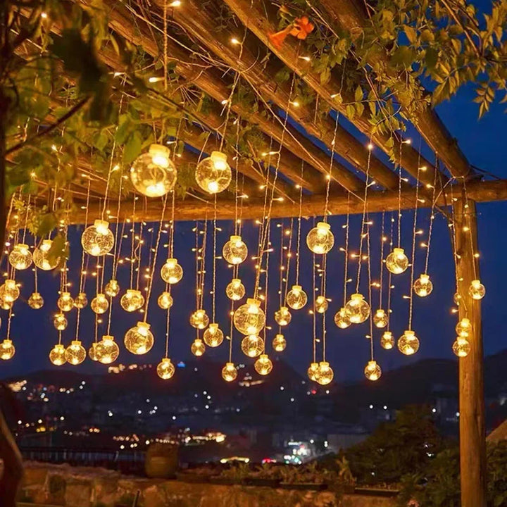 Outdoor string lights hanging across a garden setup at night
