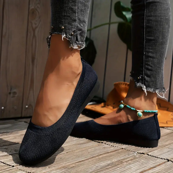 Women's navy blue breathable slip-on walking shoes paired with distressed denim jeans.