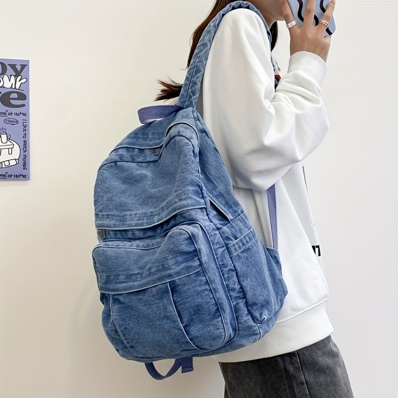 Person wearing blue denim backpack on shoulder