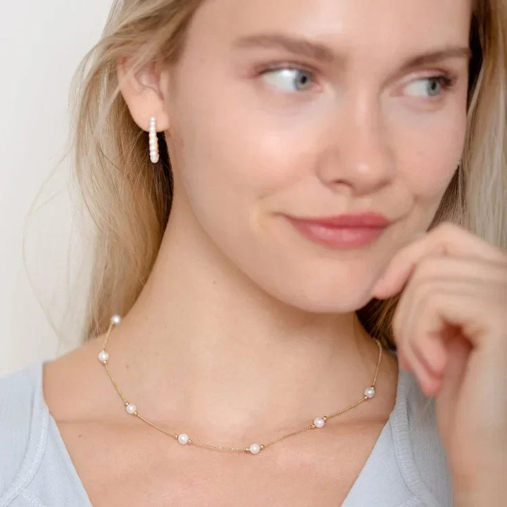 Woman wearing the elegant gold pearl necklace close-up