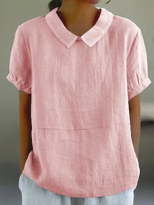 Woman wearing a light pink short sleeve shirt with a classic collar