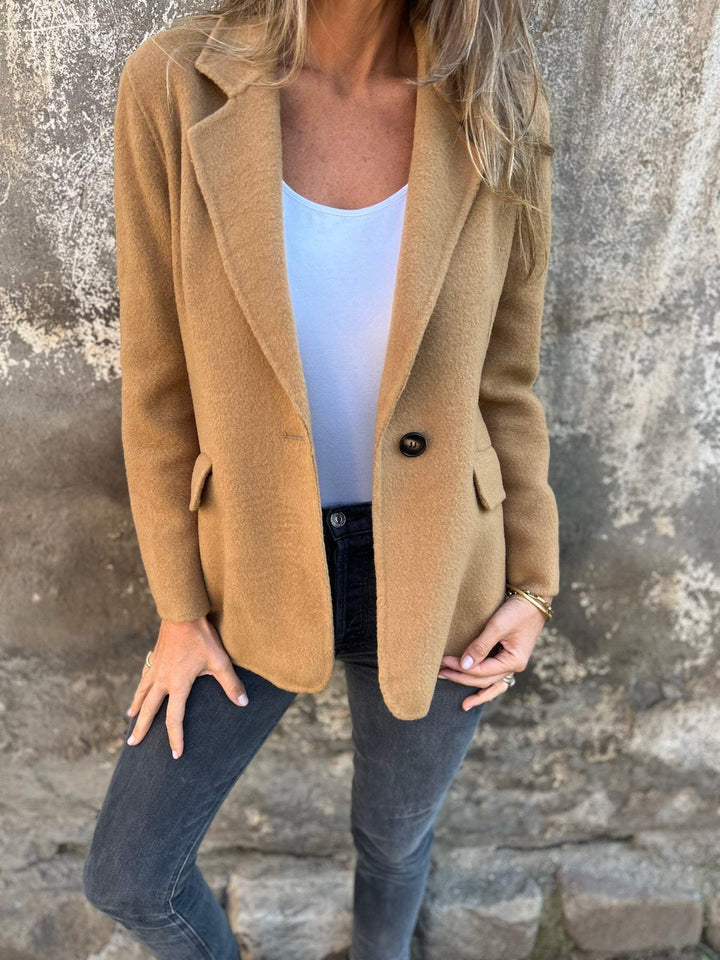 Woman wearing brown tailored blazer with white top and jeans