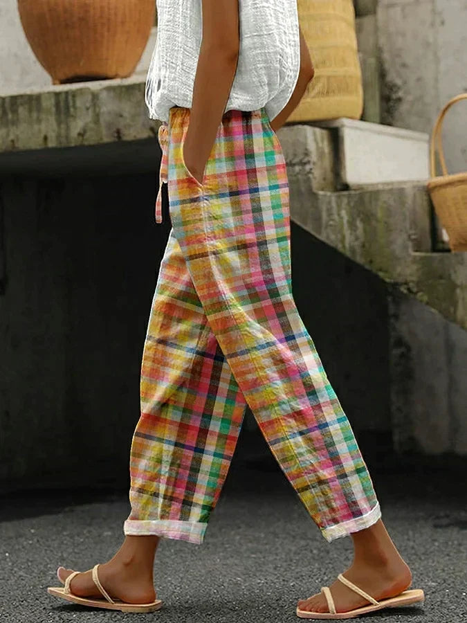 Woman wearing colorful plaid pattern trousers with white top and sandals