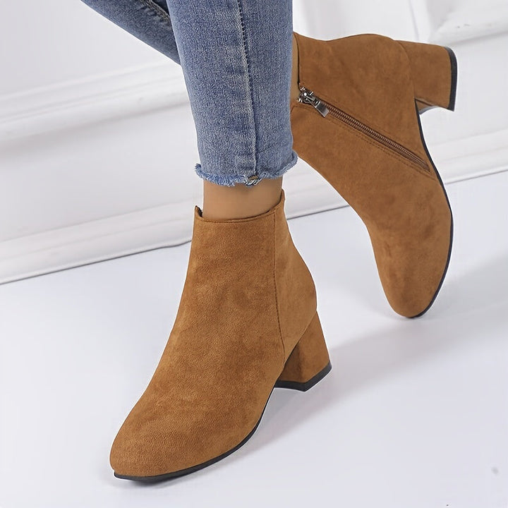 Close-up of brown ankle boots styled with blue jeans