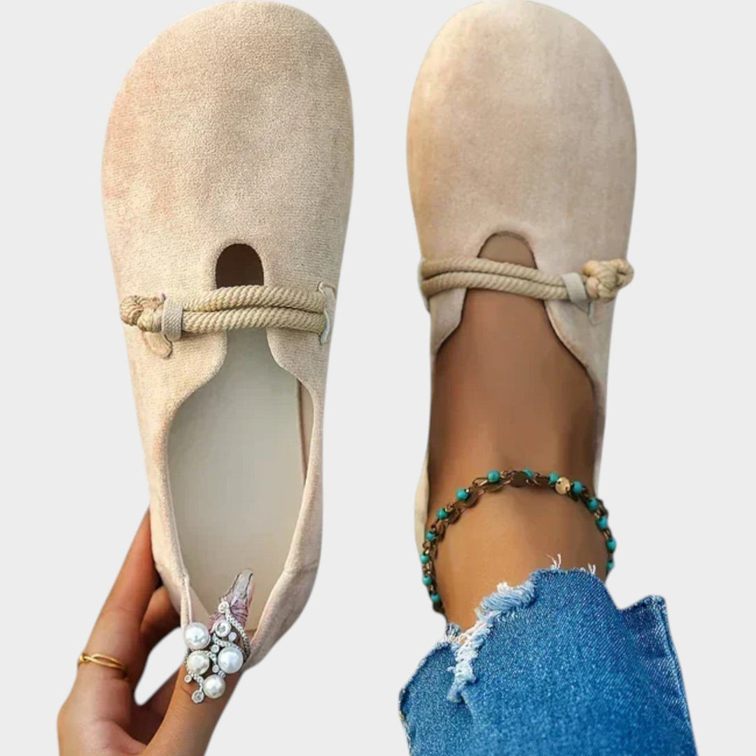 Top view of beige women's flat shoes held in hand