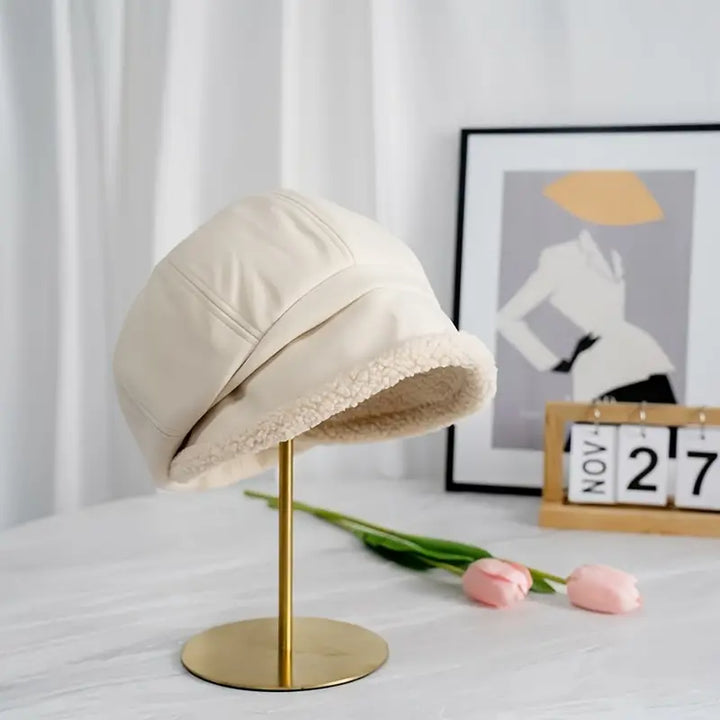 Beige winter bucket hat displayed on a golden stand with pink tulips