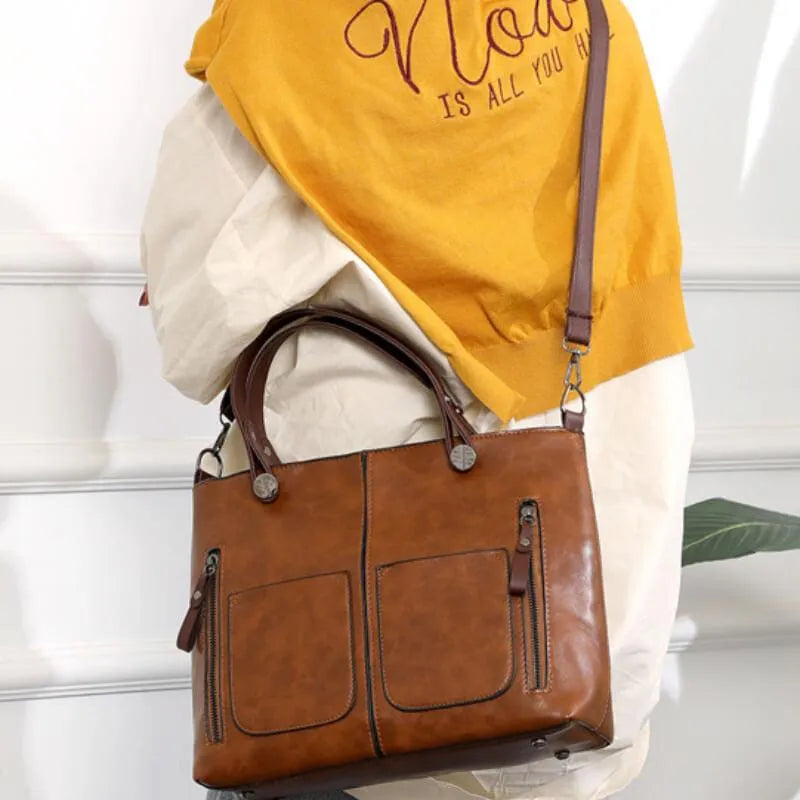 Women's brown shoulder bag showcasing multiple front zipper pockets and leather texture