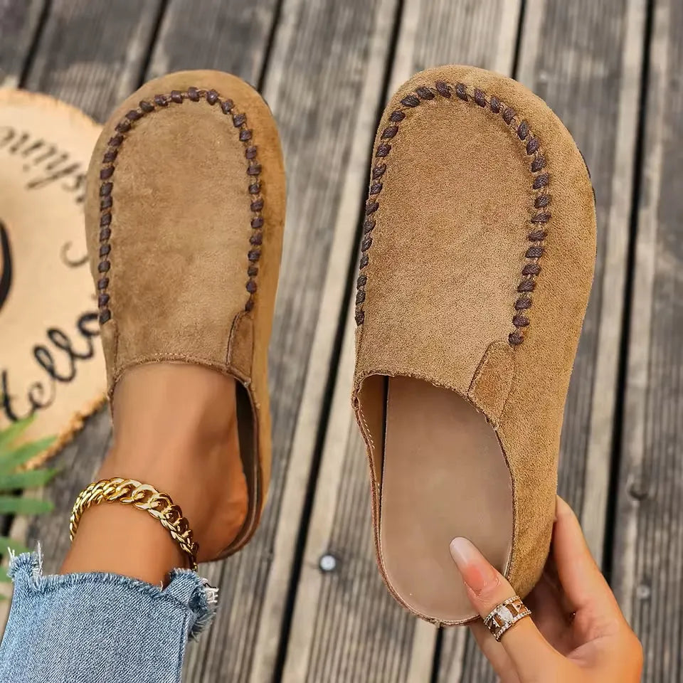 Women's brown slip-on flat orthopaedic sandals shown from above on a wooden background
