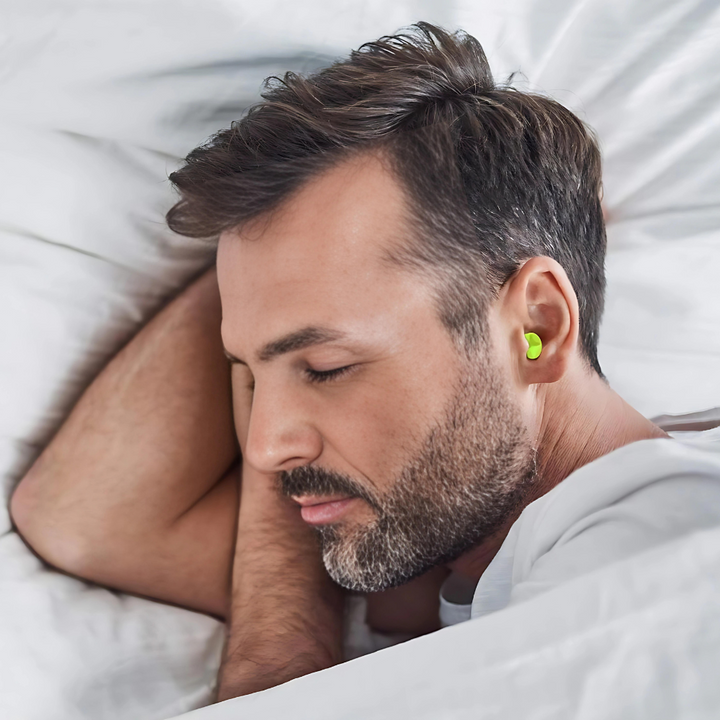 Man sleeping peacefully in bed wearing comfortable yellow earplugs