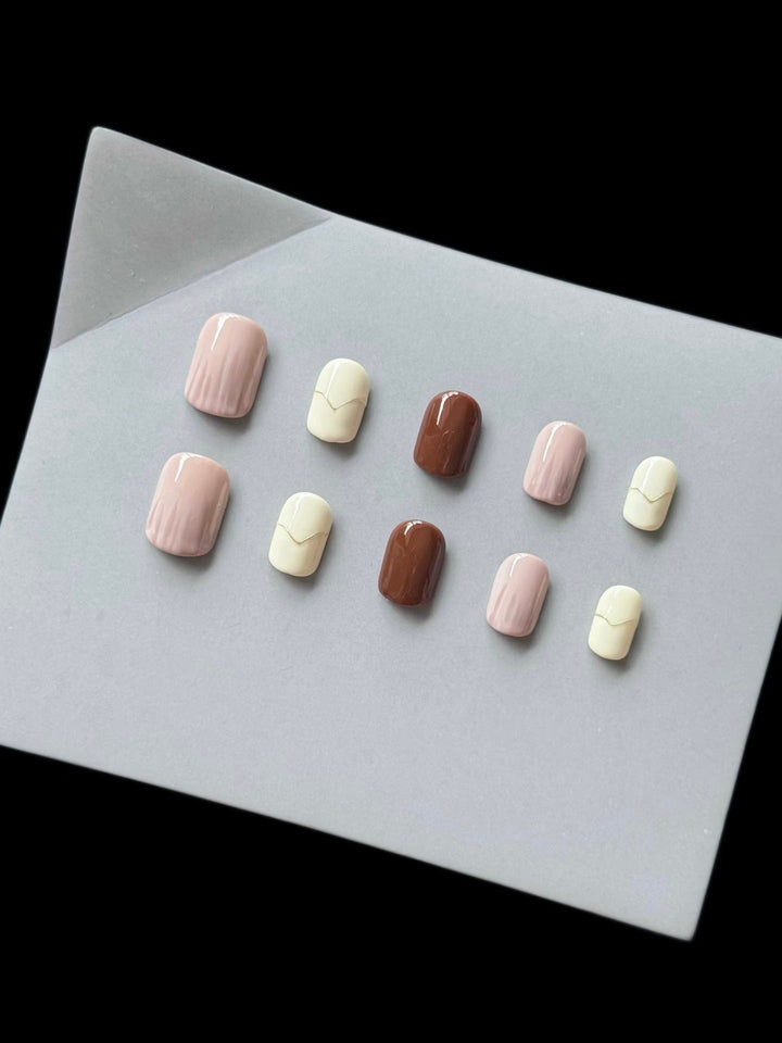 Elegant press-on nail set in pink, cream and brown displayed on a grey stand