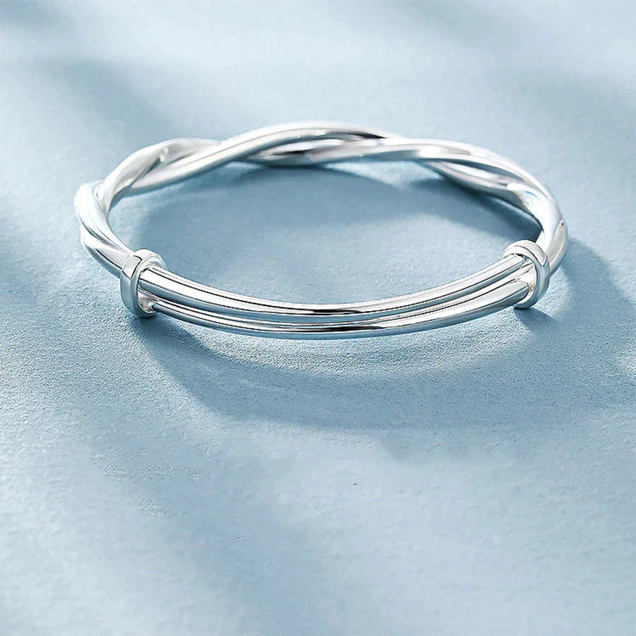 Women's elegant silver bracelet with an intricate twisted design shown from the side
