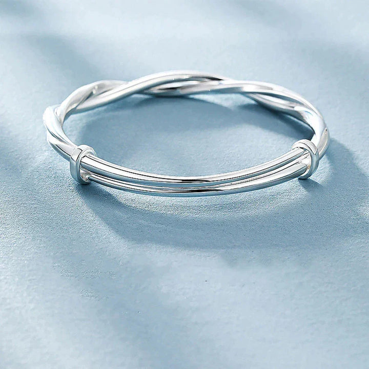 Women's elegant silver bracelet with an intricate twisted design shown from the side