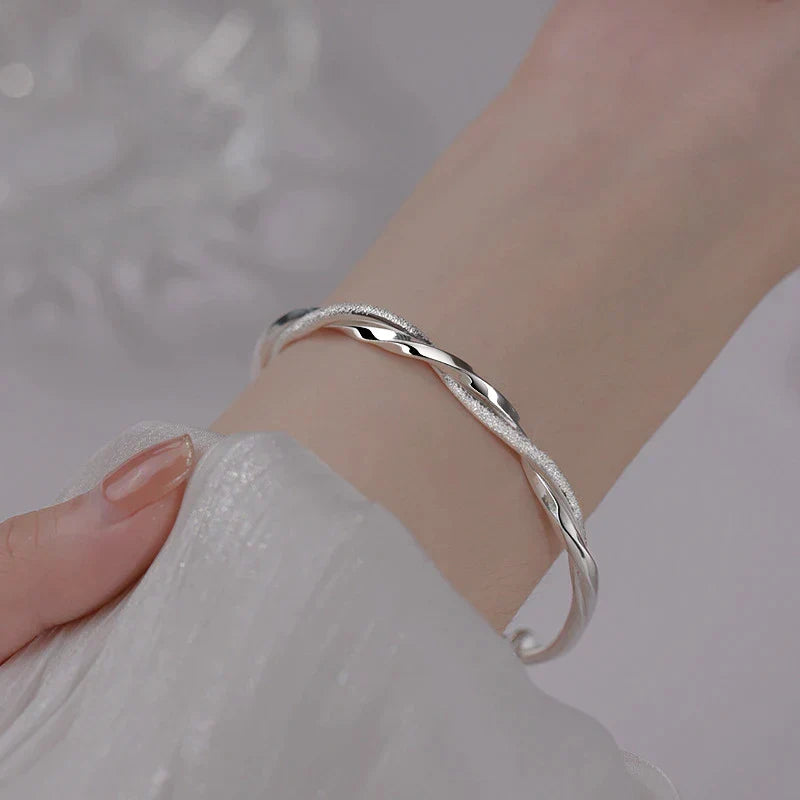 Elegant silver bracelet worn on a wrist showing intricate twisted design