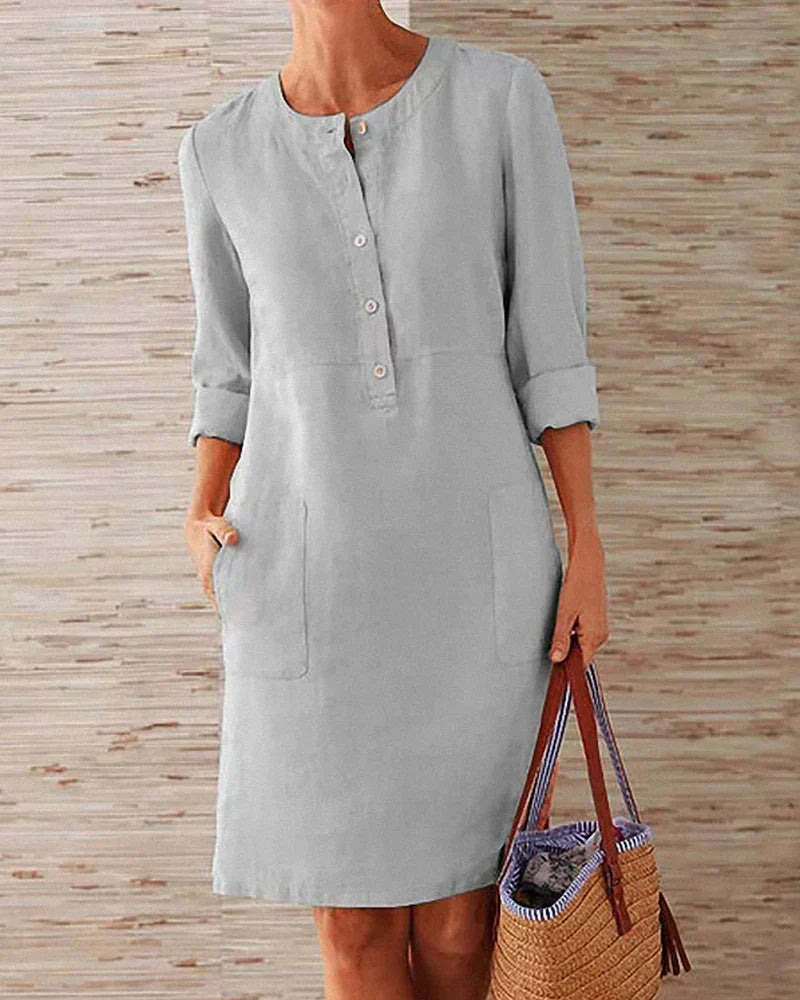 Woman wearing gray button-placket summer dress holding a straw bag
