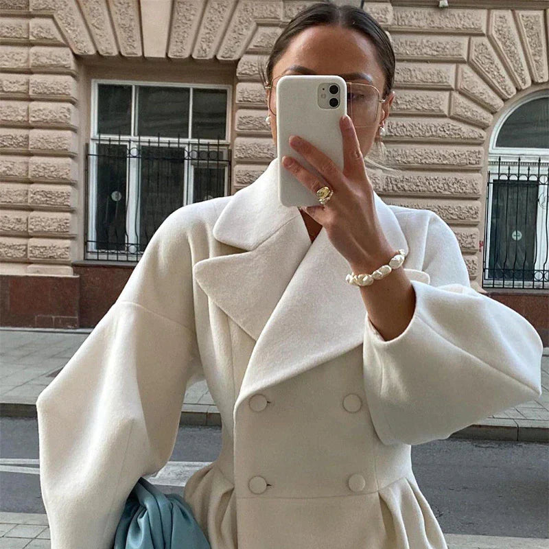 Close-up of a woman wearing a white double-breasted long coat outdoors
