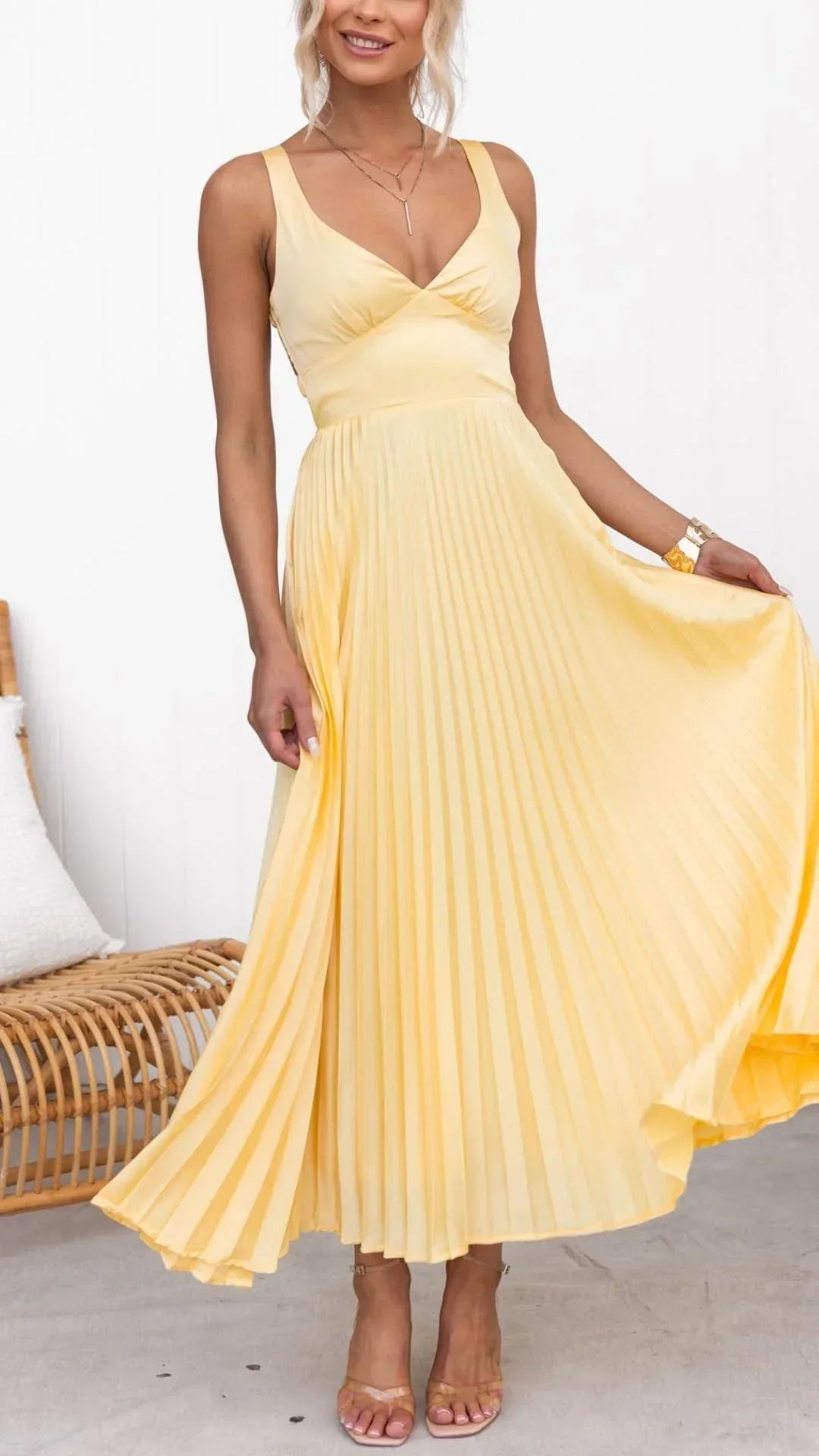 Model wearing elegant yellow pleated V-neck maxi dress holding skirt