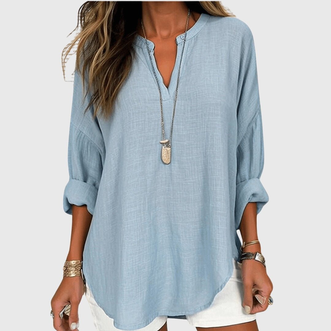 Woman wearing a light blue V-neck tunic shirt with rolled sleeves
