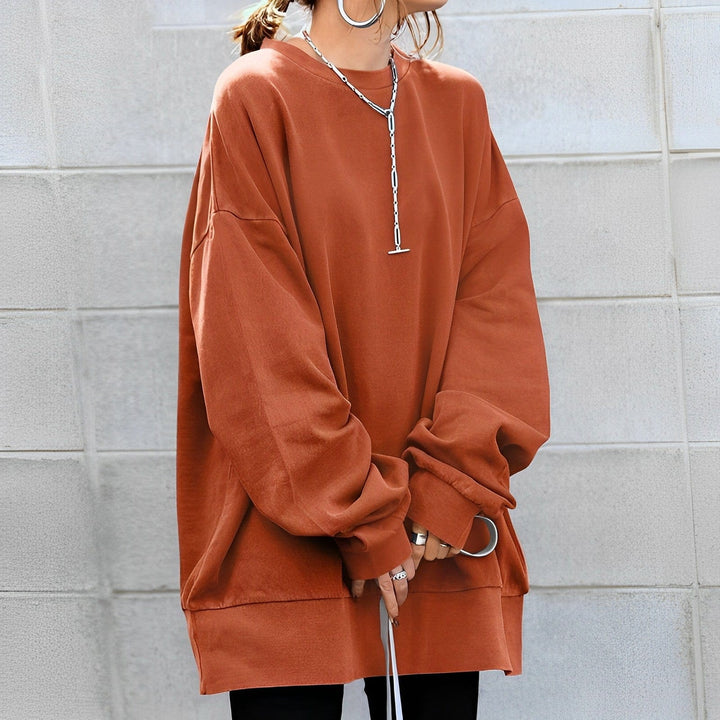 Woman wearing a rust orange oversized sweater with layered jewelry