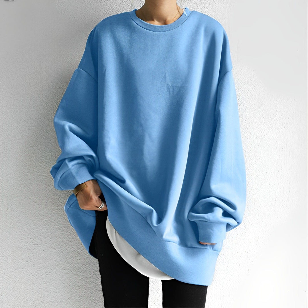 Woman wearing a light blue oversized crewneck jumper with layered hem
