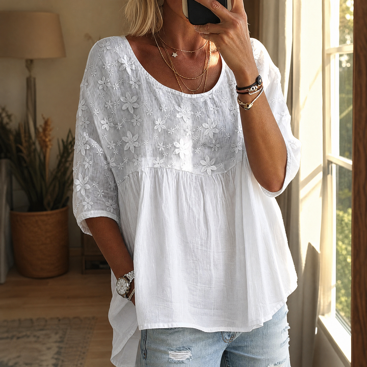 Woman wearing white floral embroidered relaxed peplum blouse with jeans
