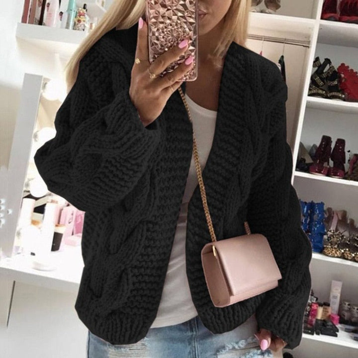 Woman wearing a black oversized cable knit cardigan with an open front design.