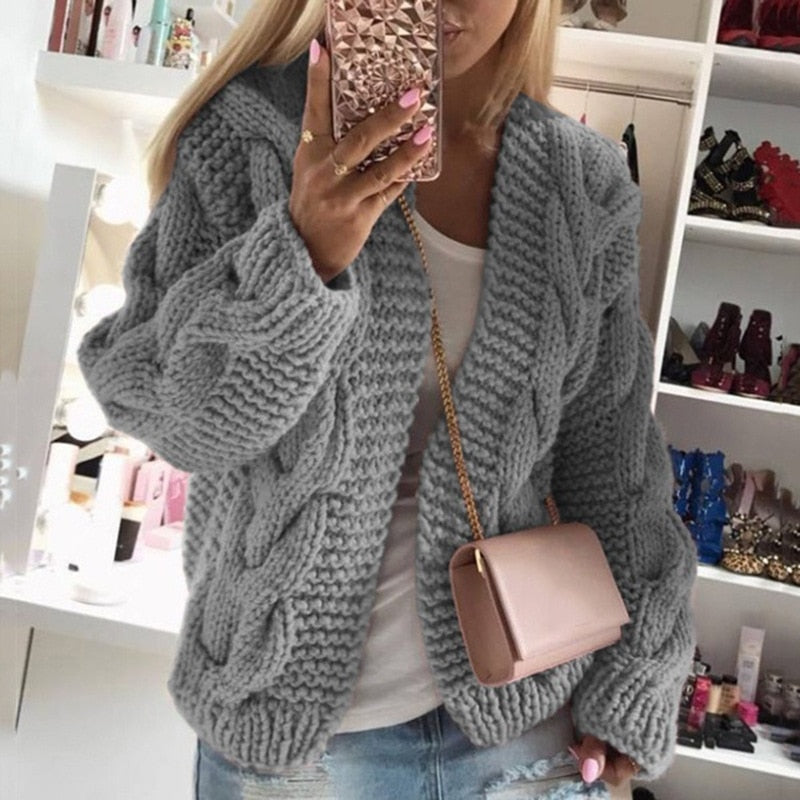Woman wearing a gray oversized cable knit cardigan showing chunky texture.