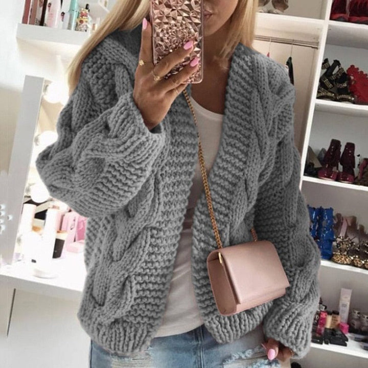 Woman wearing a gray oversized cable knit cardigan showing chunky texture.