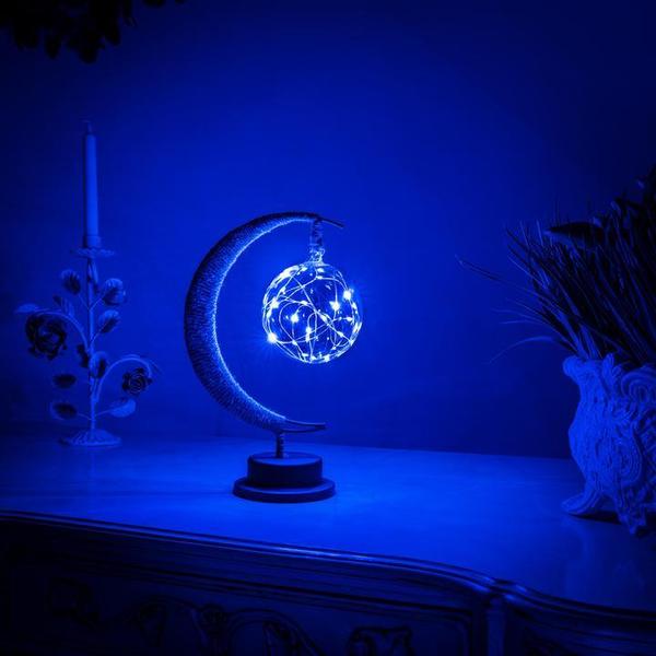 Illuminated blue crescent moon lamp glowing on a table