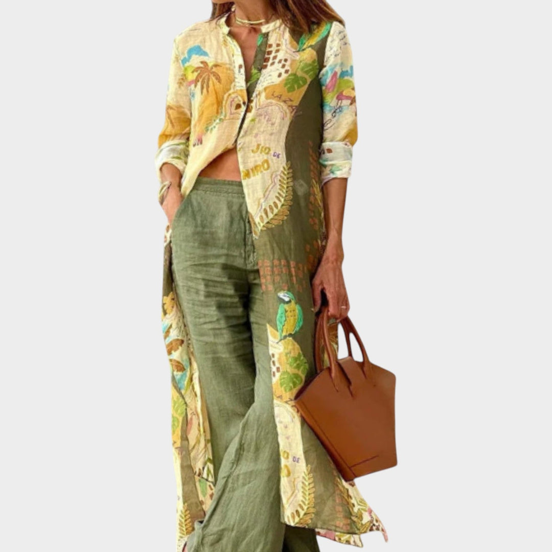 Woman wearing a green tropical printed three piece boho outfit with matching shirt and pants holding a brown handbag