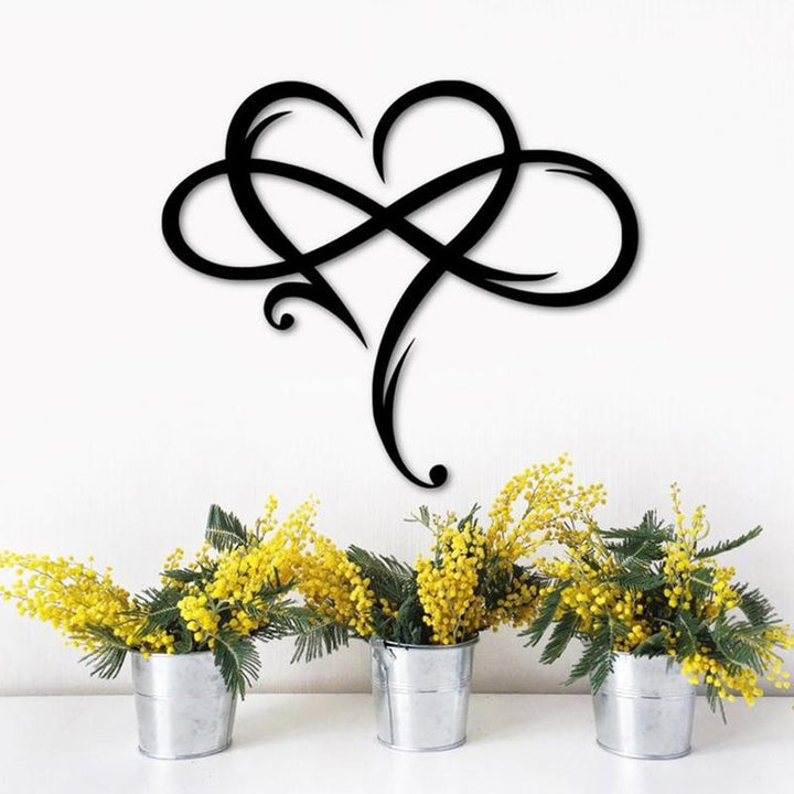 Black stainless steel infinity heart wall art displayed above flower pots