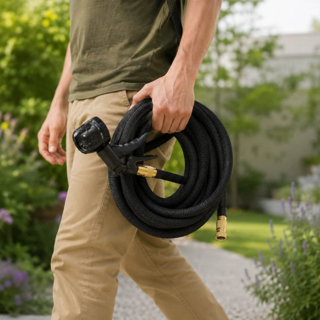 Man holding a compact black expandable garden hose outdoors