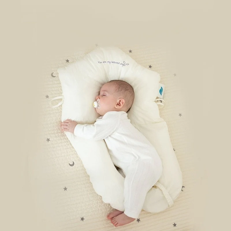 Full view of newborn resting comfortably on a soft contoured baby sleep pillow