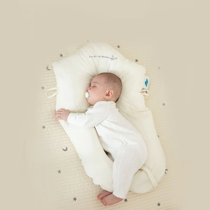 Full view of newborn resting comfortably on a soft contoured baby sleep pillow