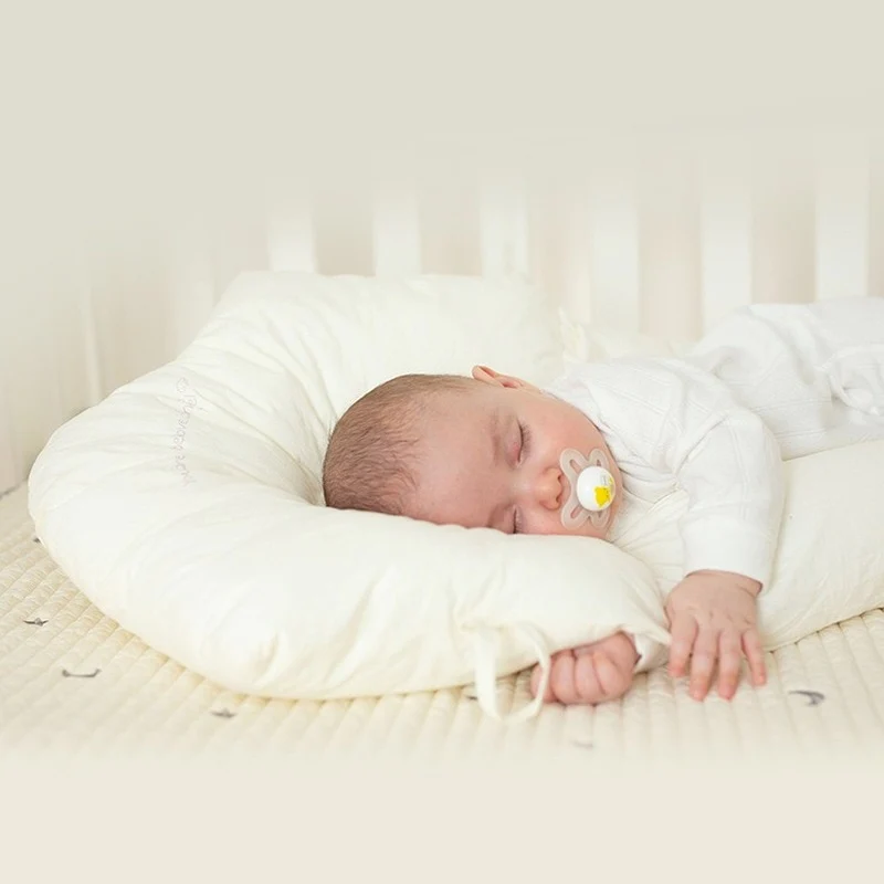 Infant hypoallergenic ergonomic sleep support pillow shown in use for newborn comfort
