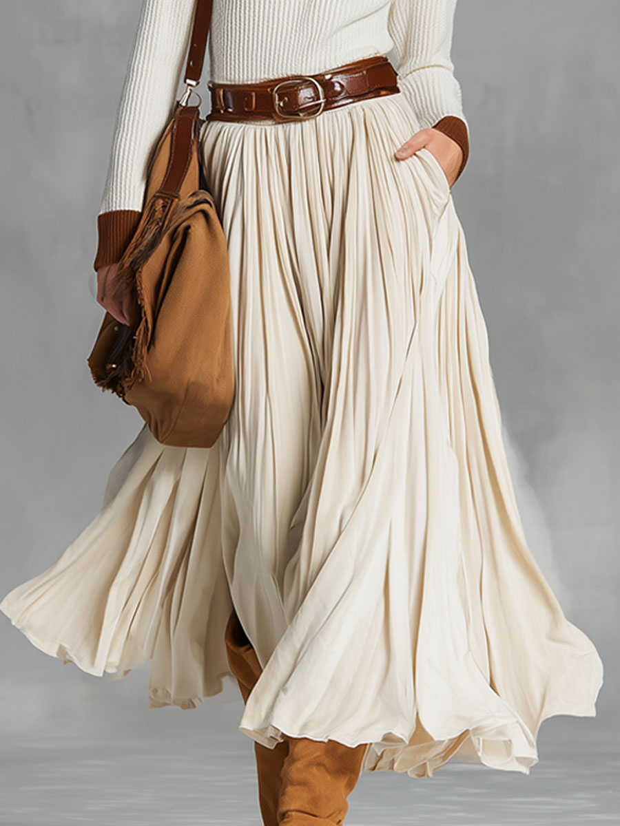Model wearing a pleated beige midi skirt with brown accessories
