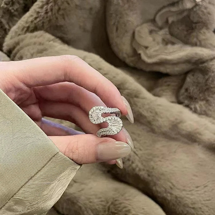 Detailed view of the S-shaped ring held against a soft background