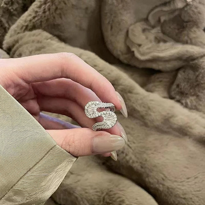Detailed view of the S-shaped ring held against a soft background
