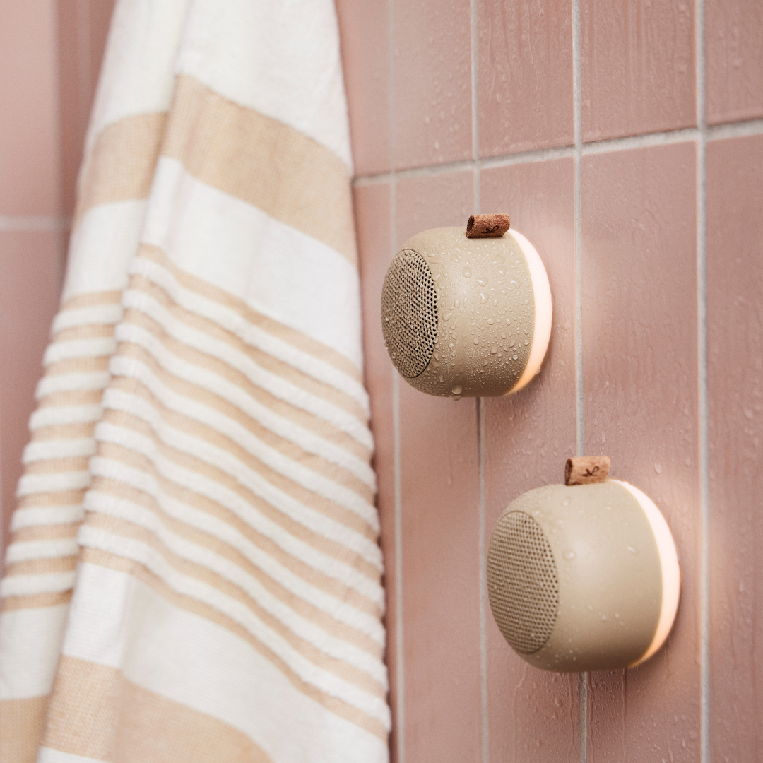 Rechargeable bathroom speaker hanging on a tile wall with soft ambient glow