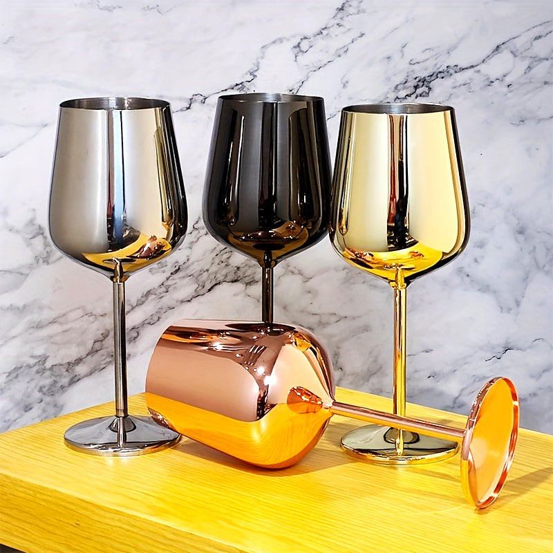 Four stainless steel wine glasses in silver, black, gold, and rose gold arranged on a marble surface.