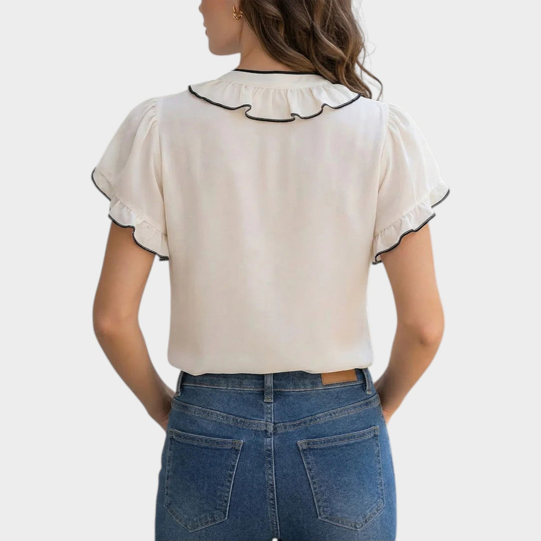 Back view of woman in white short sleeve blouse with ruffle collar detail
