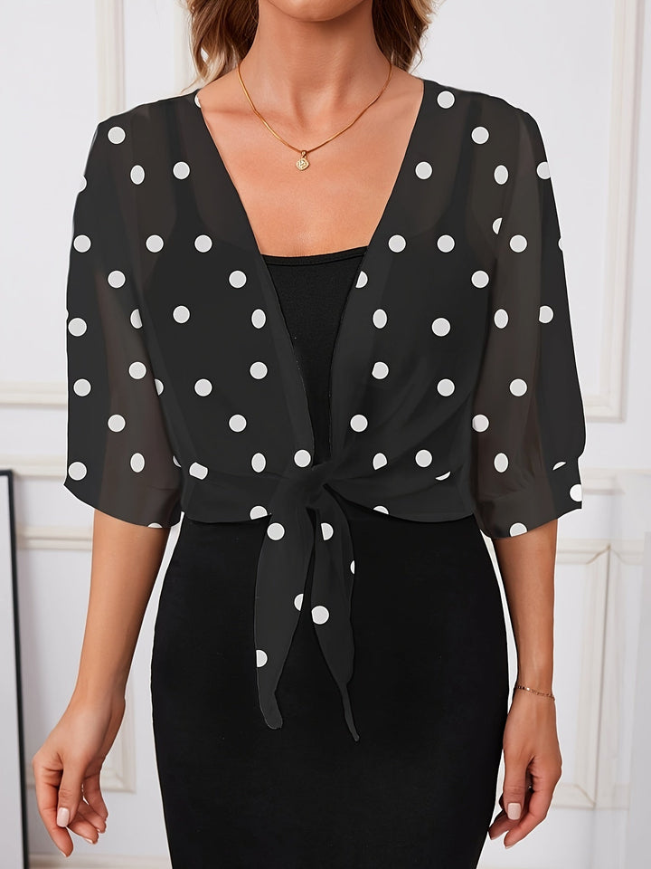 Close-up of the red polka dot pattern and tie-front hem on a stylish women's short sleeve shirt