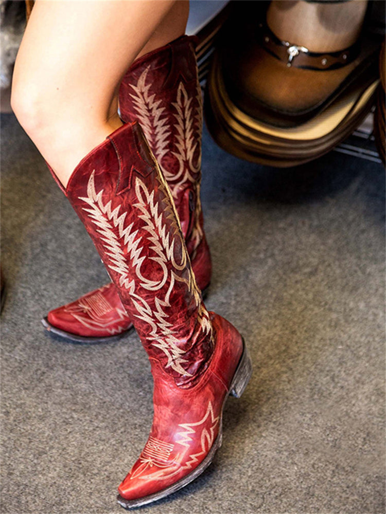Red embroidered knee-high cowboy boots displayed in a store